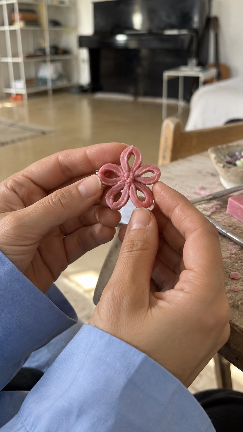 ידיים מחזיקות פרח שפוסל בשעווה ורודה